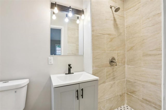 bathroom featuring toilet, a tile shower, and vanity