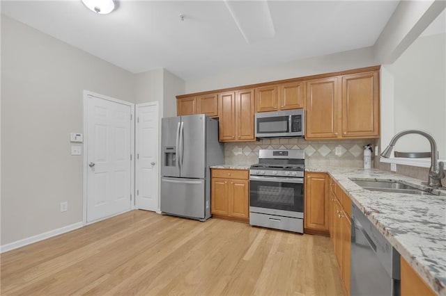 1804 Evadale Ct Unit 1, Mableton, GA 30126 - kitchen with stainless steel appliances, light stone counters, light wood-style flooring, backsplash, and brown cabinetry