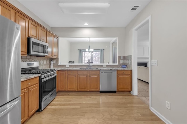 1804 Evadale Ct Unit 1, Mableton, GA 30126 - kitchen featuring appliances with stainless steel finishes, decorative backsplash, light wood finished floors, a chandelier, and light stone countertops