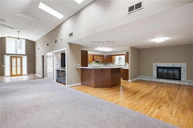 3272 Pinestream Rd NW, Atlanta, GA 30327 - kitchen featuring open floor plan, a peninsula, a kitchen breakfast bar, light wood-style floors, and brown cabinetry
