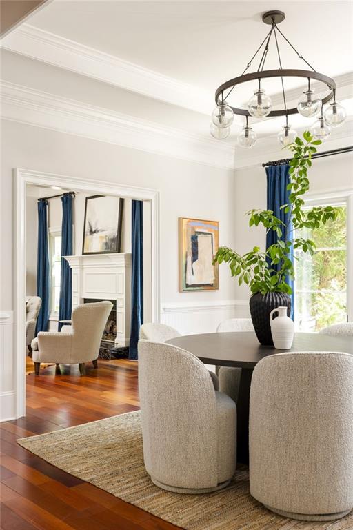 2015 N Decatur Rd NE, Atlanta, GA 30307 - dining space featuring a chandelier, a fireplace, crown molding, a wainscoted wall, and wood finished floors