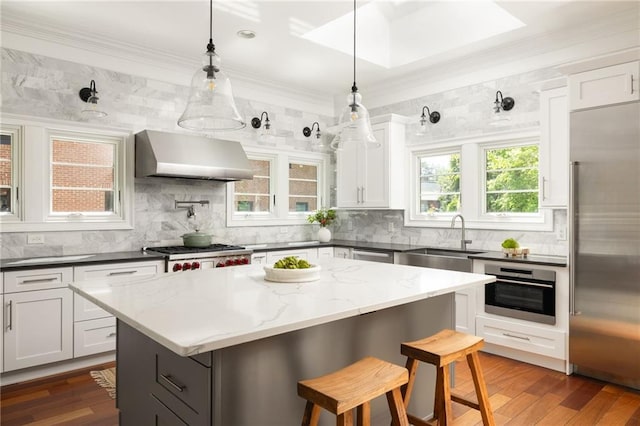 2015 N Decatur Rd NE, Atlanta, GA 30307 - kitchen featuring wall chimney range hood, a center island, a kitchen bar, appliances with stainless steel finishes, and a sink