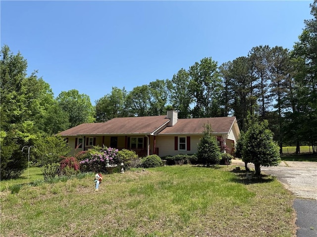 ranch-style home featuring a chimney, driveway, and a front yard