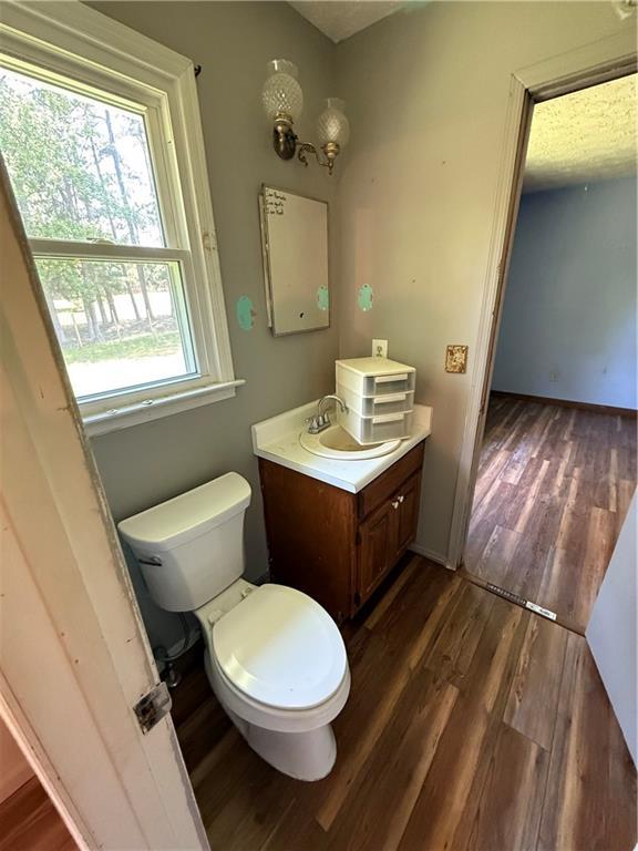 bathroom featuring vanity, baseboards, toilet, and wood finished floors