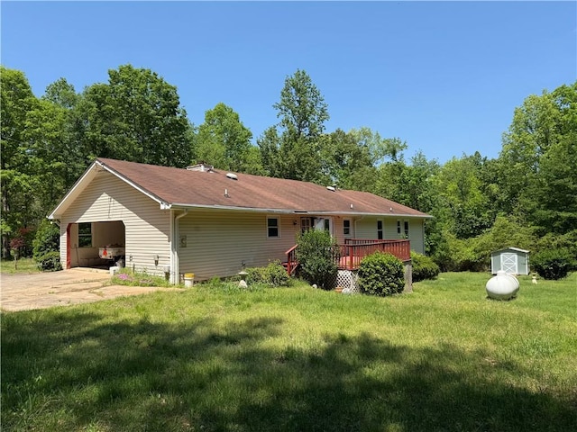 back of house with an outdoor structure, a wooden deck, a storage unit, a lawn, and driveway