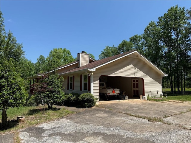 view of home's exterior featuring an attached garage, driveway, and a chimney