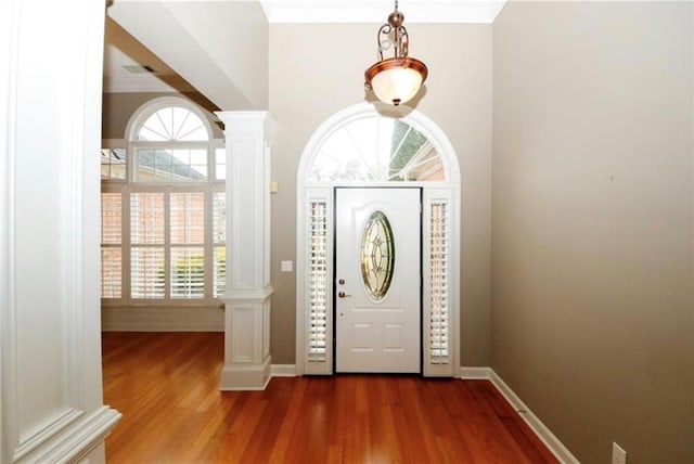 entryway with plenty of natural light, wood finished floors, and ornate columns