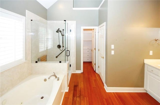 full bath featuring a garden tub, wood finished floors, a shower stall, lofted ceiling, and vanity