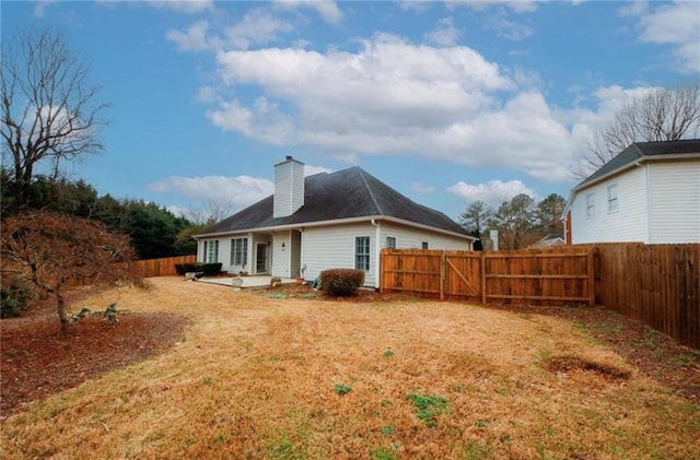 back of property featuring a yard, a fenced backyard, a chimney, and a patio area