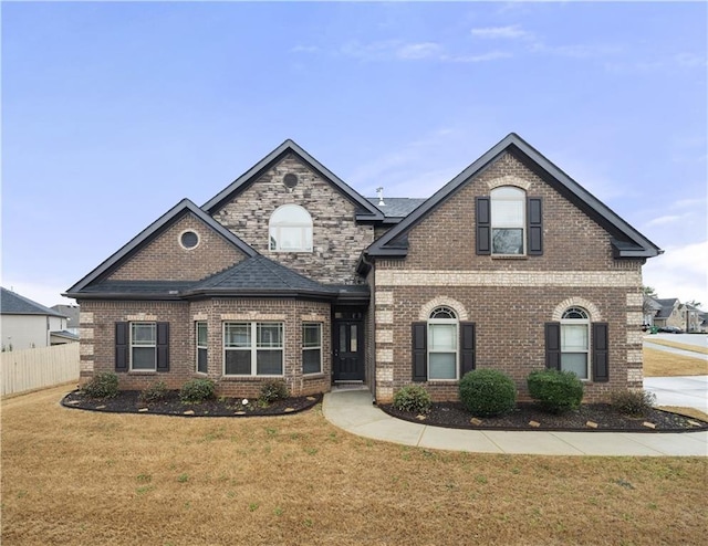 view of front of house with a front lawn, fence, and brick siding