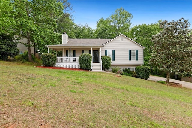 view of front facade with covered porch, a chimney, and a front lawn