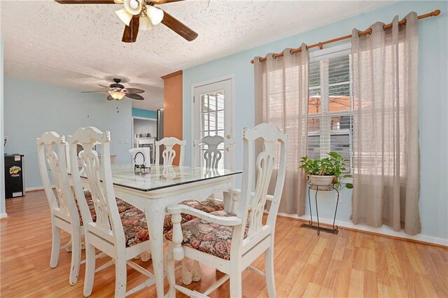 dining space with ceiling fan, light wood-style floors, a textured ceiling, and baseboards