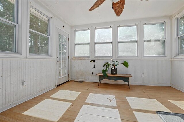 sunroom / solarium featuring wood finished floors, baseboards, and wood walls