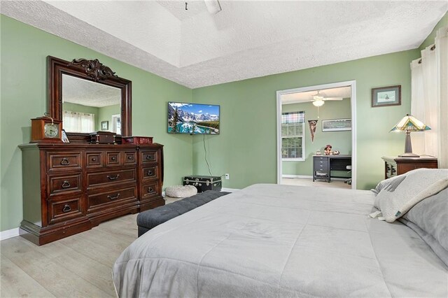 bedroom with a textured ceiling, wood finished floors, baseboards, and ceiling fan