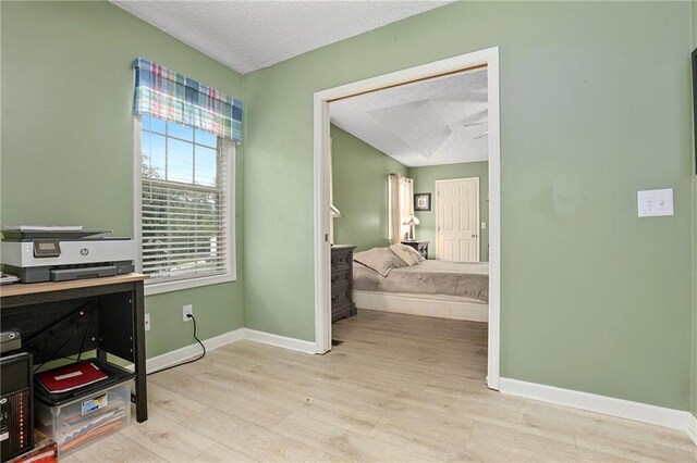 office space with light wood-style floors, baseboards, and a textured ceiling