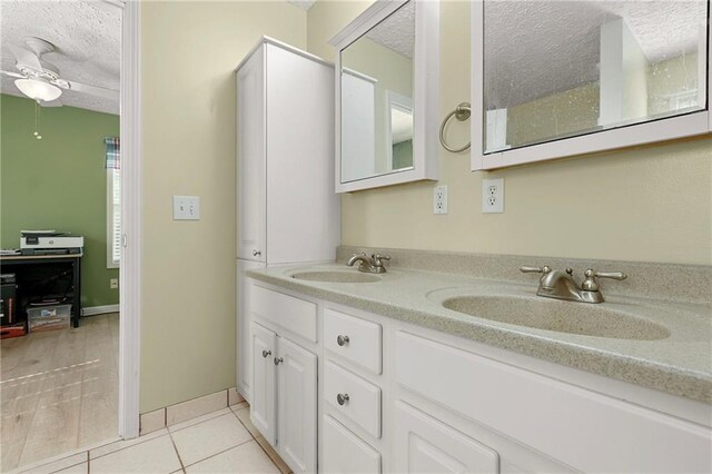 full bath featuring a textured ceiling, a ceiling fan, double vanity, and tile patterned flooring