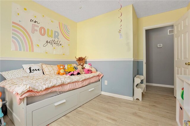 bedroom featuring wood finished floors, a textured ceiling, and baseboards