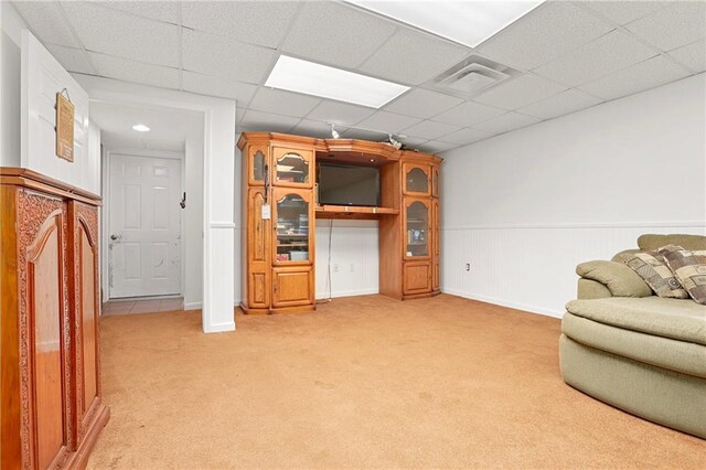 sitting room with light carpet, a drop ceiling, and baseboards