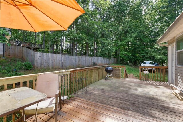 deck with fence and view of wooded area