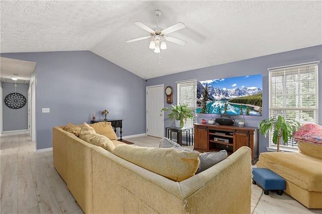 living room with a textured ceiling, vaulted ceiling, ceiling fan, light wood finished floors, and baseboards