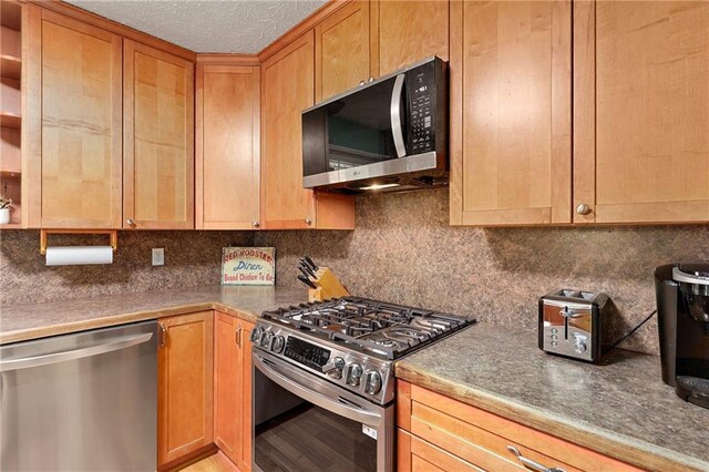 kitchen featuring appliances with stainless steel finishes, decorative backsplash, light brown cabinets, and a textured ceiling