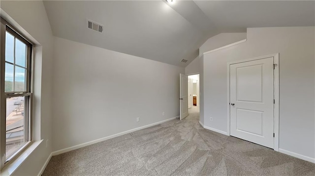 unfurnished bedroom featuring vaulted ceiling, light colored carpet, visible vents, and baseboards