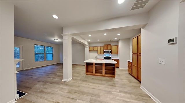 kitchen featuring light wood finished floors, visible vents, open floor plan, appliances with stainless steel finishes, and a sink