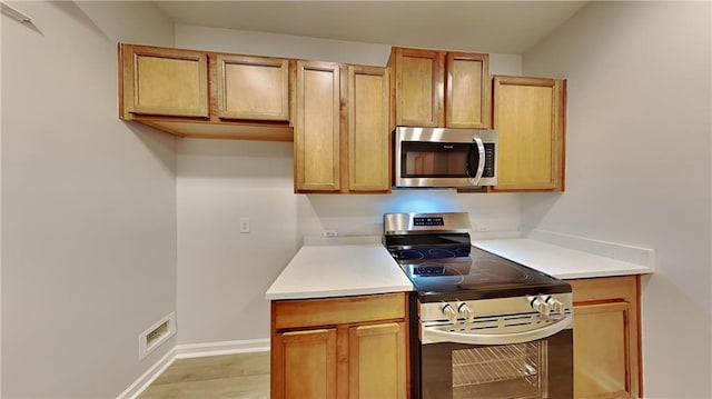 kitchen featuring light countertops, light wood-style floors, baseboards, and appliances with stainless steel finishes