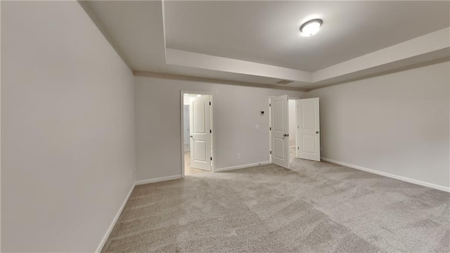 unfurnished bedroom featuring connected bathroom, carpet, a raised ceiling, and baseboards