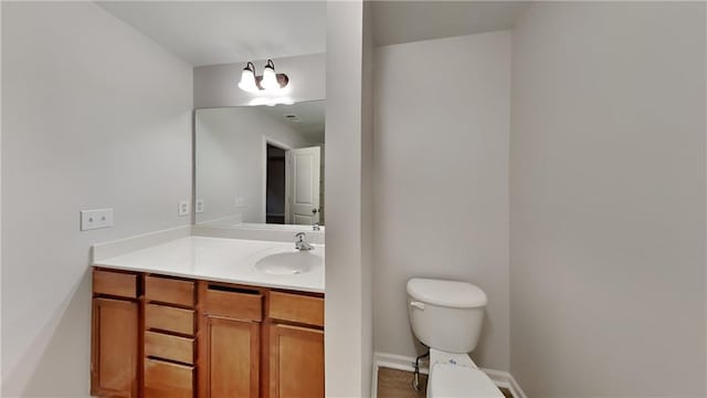 bathroom featuring baseboards, toilet, and vanity