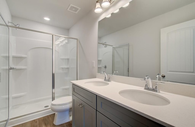 bathroom featuring toilet, vanity, a shower with door, and hardwood / wood-style floors