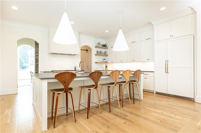 3338 Breton Cir NE, Brookhaven, GA 30319 - kitchen with crown molding, arched walkways, light wood-style floors, decorative backsplash, and white cabinetry