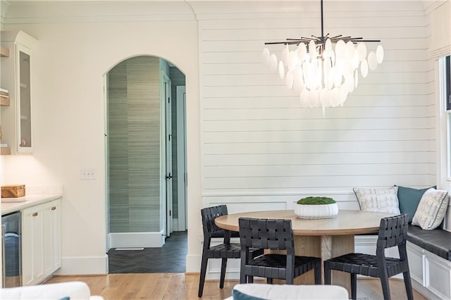 3338 Breton Cir NE, Brookhaven, GA 30319 - dining area with light wood-style flooring, a chandelier, arched walkways, baseboards, and beverage cooler