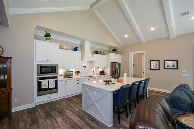 kitchen featuring custom exhaust hood, white cabinetry, stainless steel appliances, and an island with sink