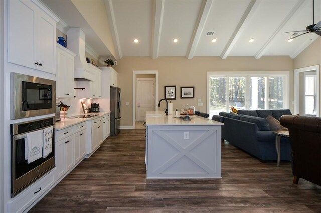 kitchen with stainless steel appliances, ceiling fan, dark wood-type flooring, white cabinets, and vaulted ceiling with beams