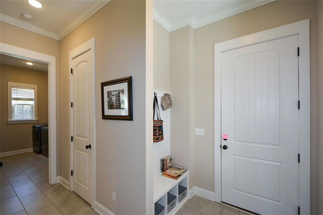 corridor featuring washer and dryer, light tile patterned flooring, and crown molding