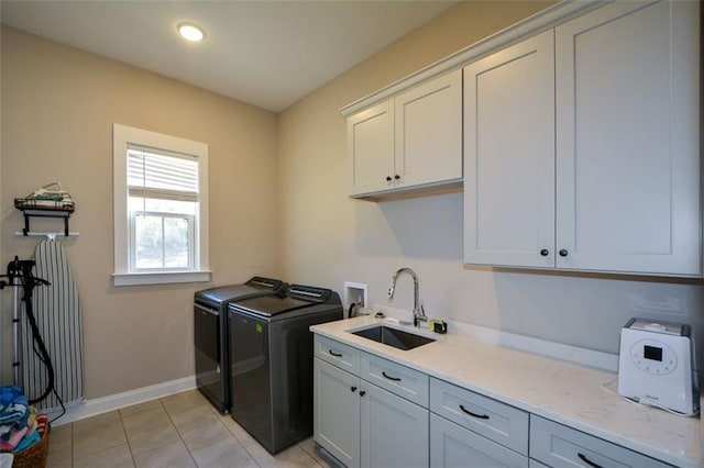 clothes washing area featuring cabinets, light tile patterned floors, washer and clothes dryer, and sink