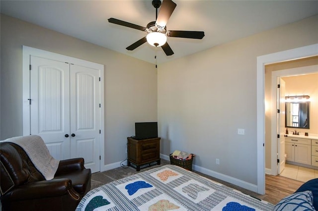 bedroom featuring ceiling fan, light hardwood / wood-style flooring, ensuite bathroom, and a closet