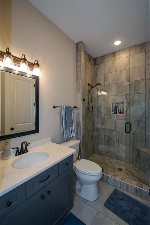 bathroom with tile patterned floors, a shower with door, vanity, and toilet