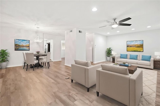 unfurnished living room with ceiling fan with notable chandelier and hardwood / wood-style flooring