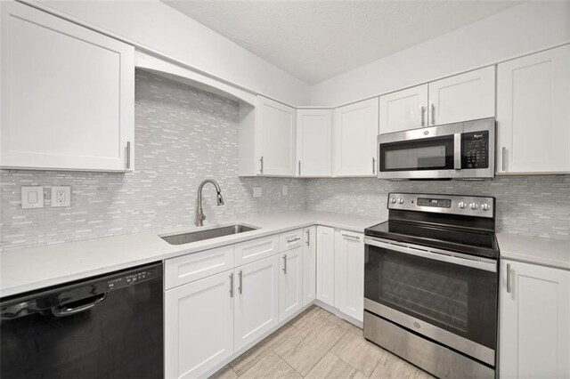 kitchen featuring white cabinets, appliances with stainless steel finishes, backsplash, and sink