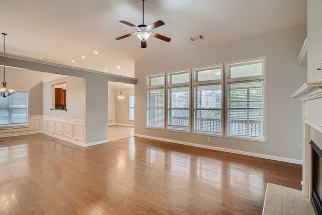 unfurnished living room featuring ceiling fan with notable chandelier, a high end fireplace, and hardwood / wood-style floors