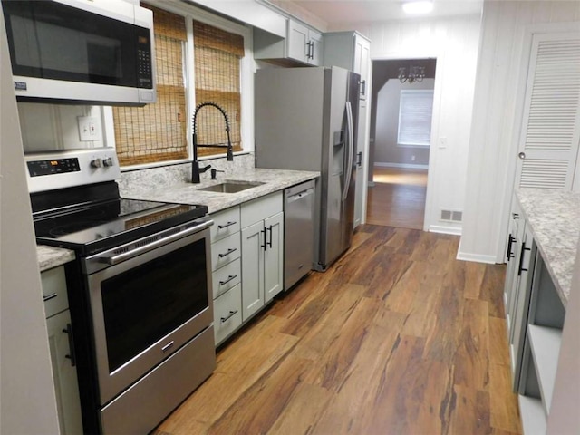 893 Andrews Dr, Conyers, GA 30012 - kitchen with appliances with stainless steel finishes, a sink, wood finished floors, and light stone counters
