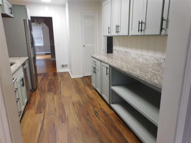 893 Andrews Dr, Conyers, GA 30012 - kitchen featuring open shelves, gray cabinetry, dark wood-type flooring, light stone counters, and freestanding refrigerator