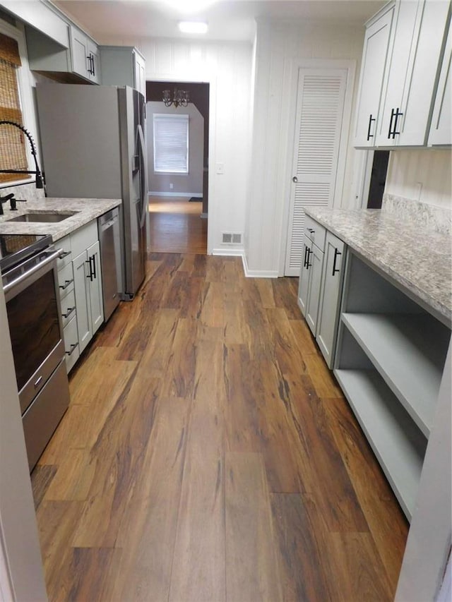 893 Andrews Dr, Conyers, GA 30012 - kitchen featuring stainless steel appliances, dark wood-type flooring, a chandelier, and light stone counters