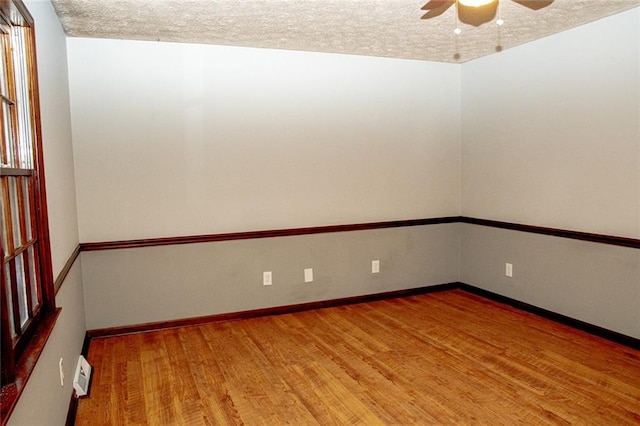 empty room featuring ceiling fan, wood-type flooring, and a textured ceiling