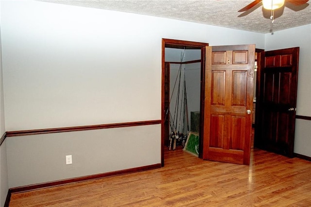 unfurnished bedroom with ceiling fan, a closet, a textured ceiling, and light hardwood / wood-style flooring