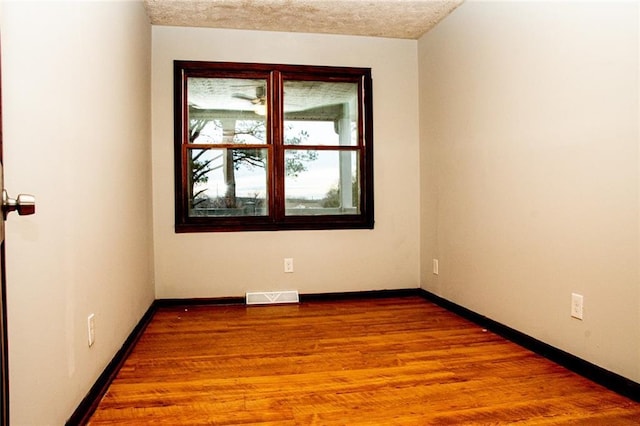 spare room featuring a textured ceiling and wood-type flooring