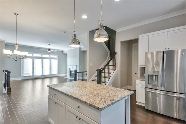 kitchen with stainless steel refrigerator with ice dispenser, pendant lighting, white cabinets, and light stone counters