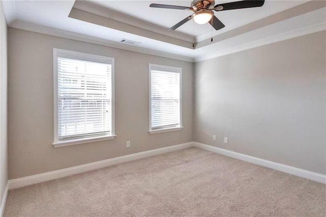 unfurnished room featuring light carpet, a tray ceiling, crown molding, and ceiling fan